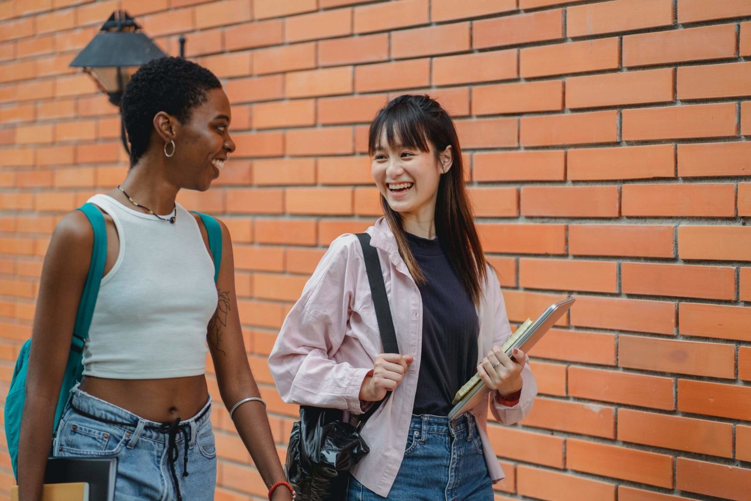 a couple of women standing next to a brick wall
