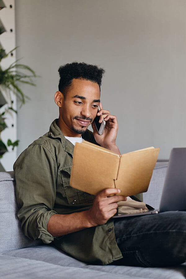 a man sitting on a couch talking on a cell phone