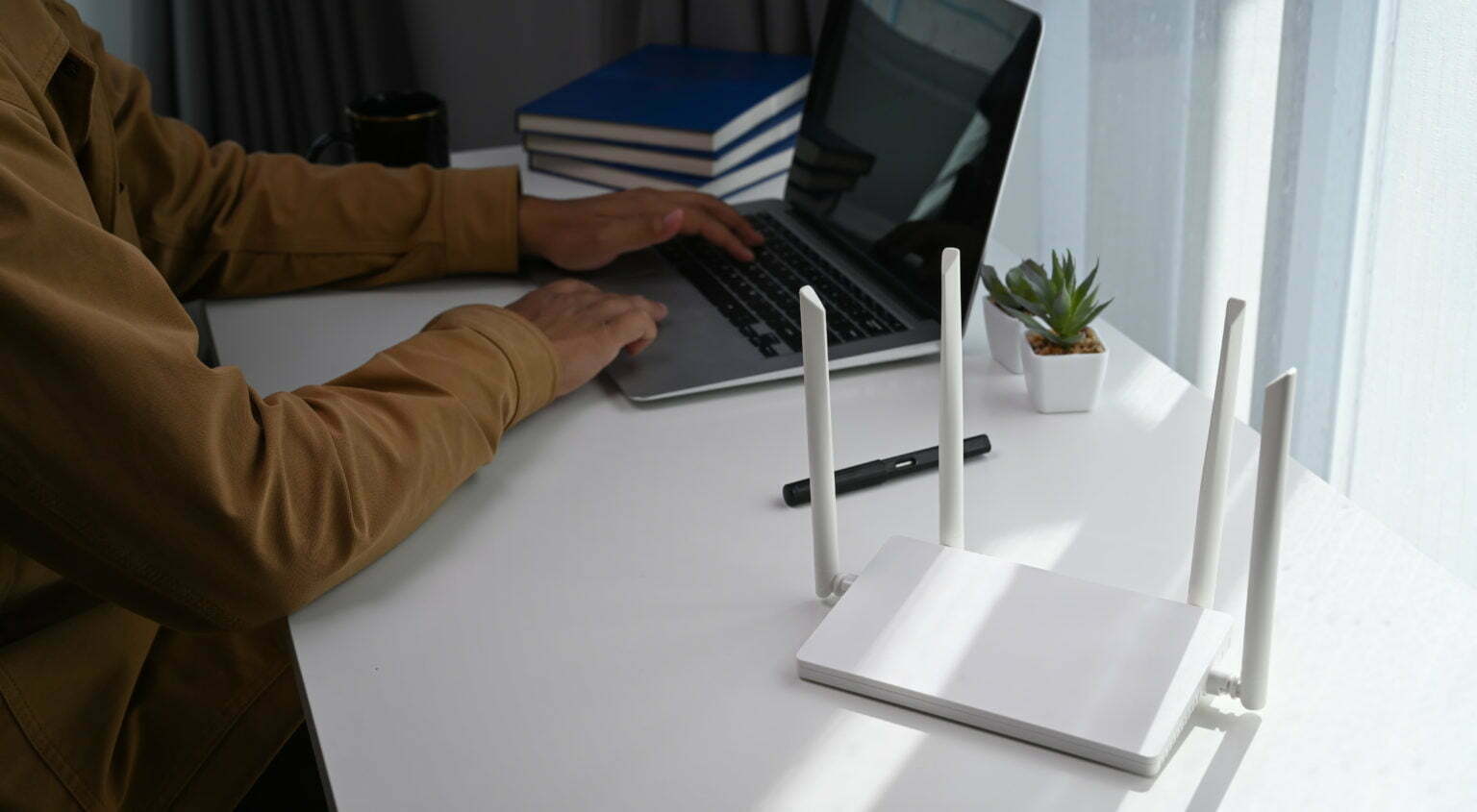 Young man working on computer laptop and sitting in front of high speed wireless internet router